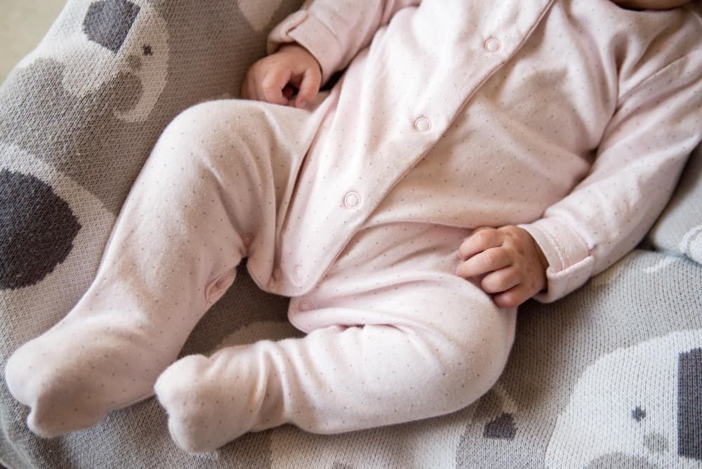 a baby in white baby clothes made from French Terry fabric