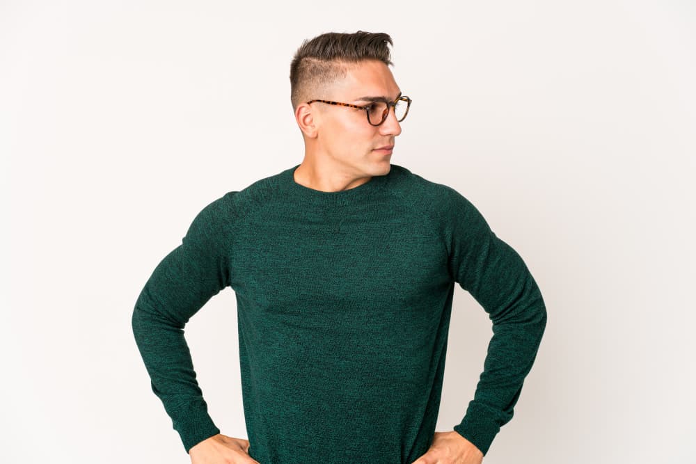 The man wearing glasses was dressed in a green garment made from the same fabric as a long-sleeved shirt.